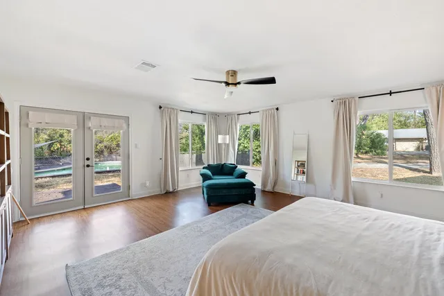 a spacious bedroom with a balcony a bed and wooden floor