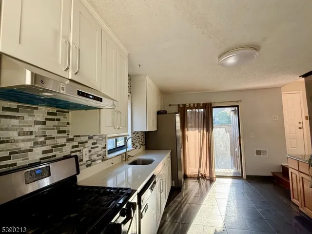 a kitchen with stainless steel appliances granite countertop a refrigerator a sink and white cabinets
