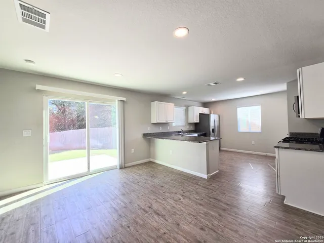 a large kitchen with stainless steel appliances granite countertop a stove a sink a refrigerator and white cabinets