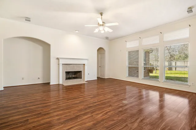 a view of an empty room with wooden floor and a fireplace