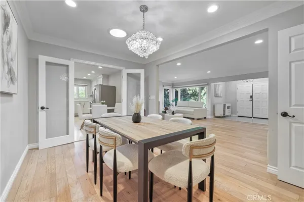 a dining room with wooden floor a chandelier a wooden table and chairs