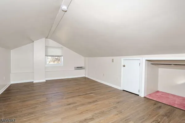 a view of an empty room with wooden floor and closet