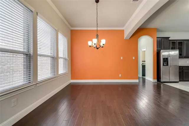 a view of a room with wooden floor chandelier and windows