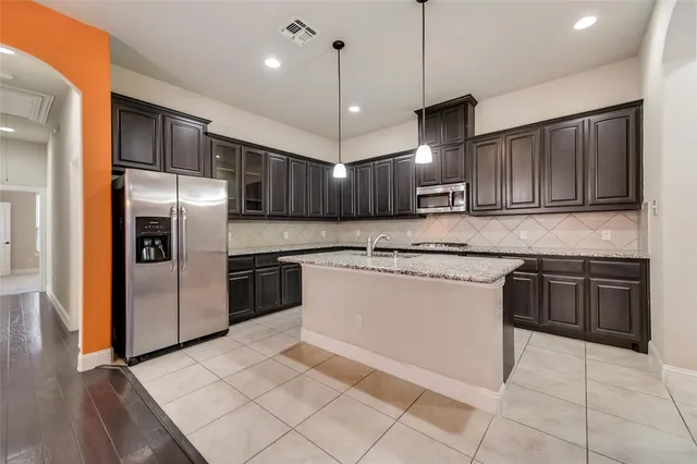 a kitchen with kitchen island granite countertop wooden cabinets stainless steel appliances and a counter top space