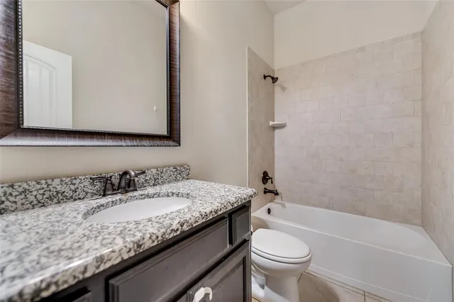 a bathroom with a granite countertop sink a toilet and a bathtub