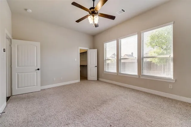 a view of an empty room with a window and a kitchen