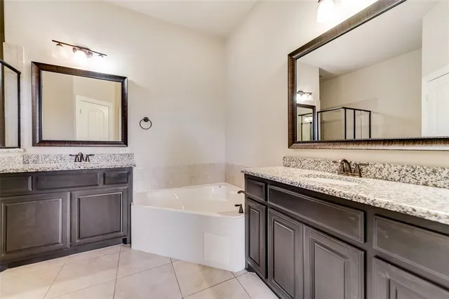 a bathroom with a granite countertop bathtub sink double and mirror