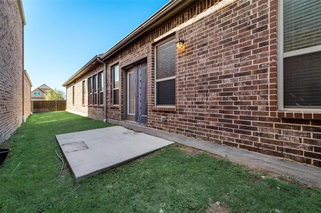 a view of a house with brick walls and a yard with a wooden fence