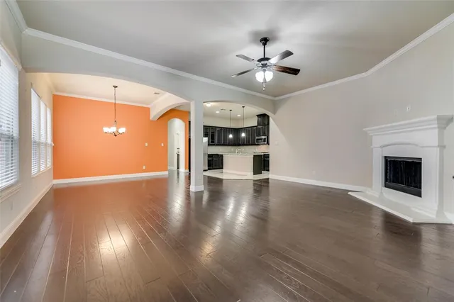 a view of a livingroom with wooden floor a ceiling fan and windows