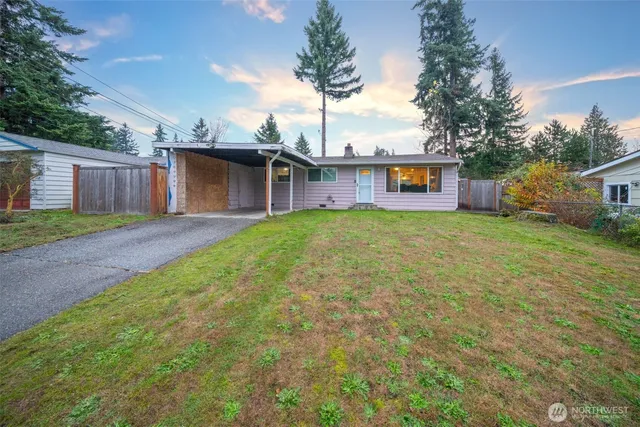 a view of a house with a yard and a large tree