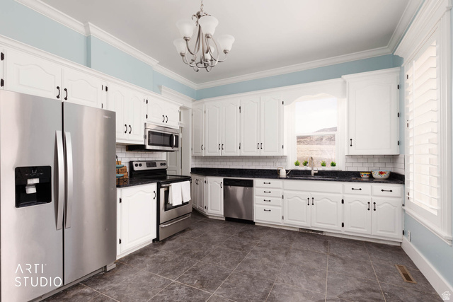 1331 South Lowry Hl Road Manti, UT 84642 - Photo 22 of 56 Kitchen featuring stainless steel appliances, white cabinetry, a chandelier, crown molding, and backsplash