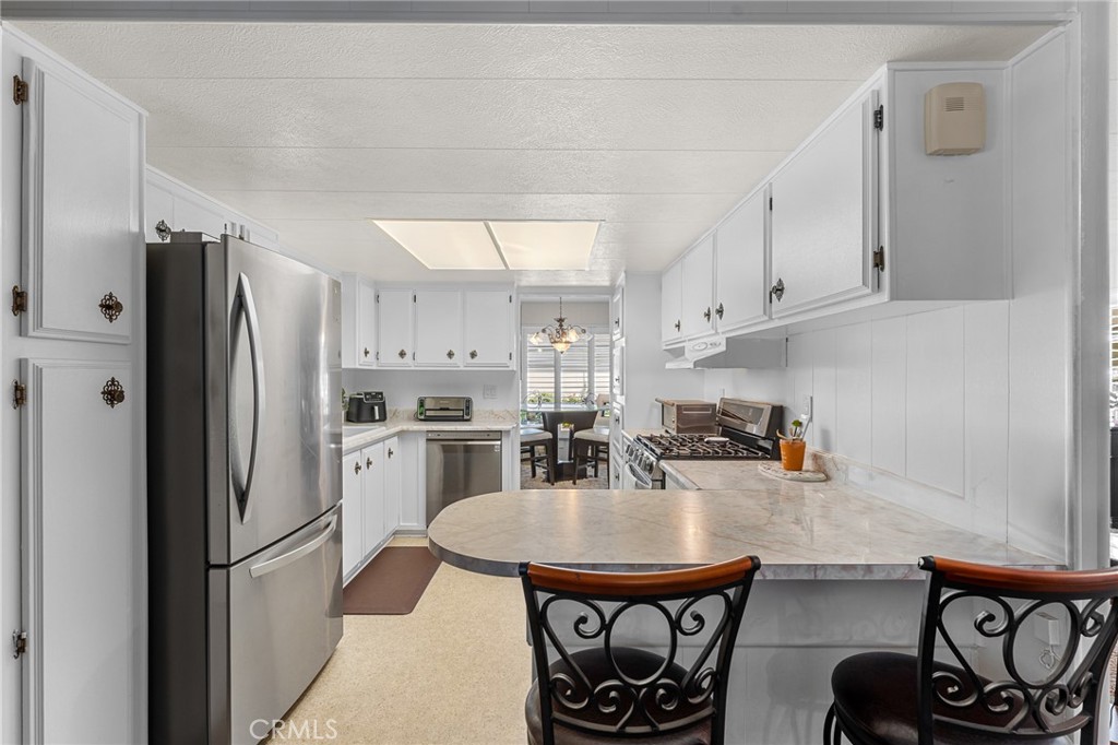 975 California Street, Unit 49 Calimesa, CA 92320 - Photo 10 of 31 a kitchen with stainless steel appliances a refrigerator a stove a sink dishwasher with a dining table and chairs