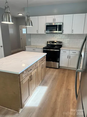 a kitchen with stainless steel appliances a sink dishwasher a stove top oven a refrigerator and a stove