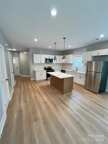 a large kitchen with stainless steel appliances a large counter top a sink a refrigerator and a stove