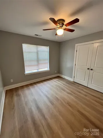 an empty room with wooden floor fan and windows