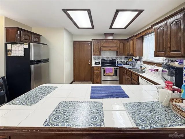 a kitchen with stainless steel appliances kitchen island granite countertop a refrigerator stove and sink