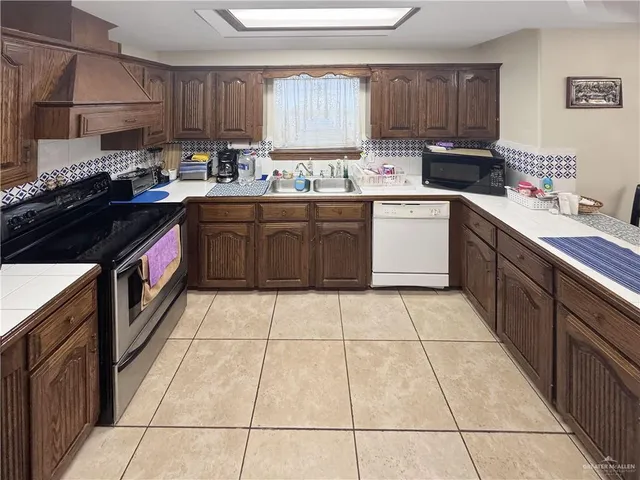a kitchen with a sink a stove a counter space and cabinets