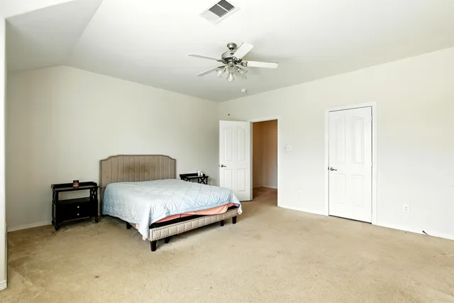 a spacious bedroom with a bed and a chandelier