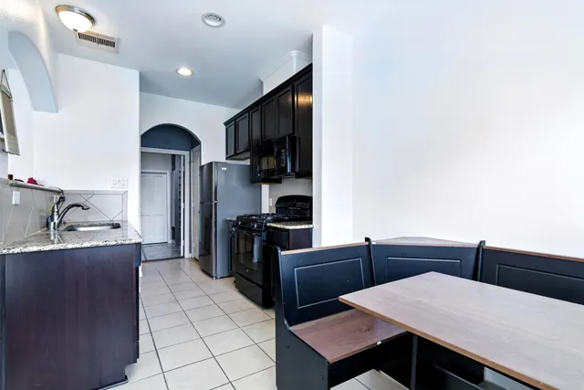 a living room with stainless steel appliances furniture a rug and a kitchen view