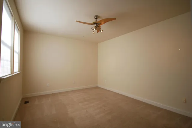 an empty room with a window and a ceiling fan