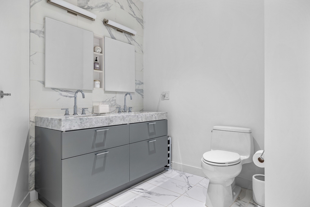 300 Pier 4 Blvd., Unit PHR Boston, MA 02210 - Photo 12 of 28 a bathroom with a granite countertop toilet sink and mirror