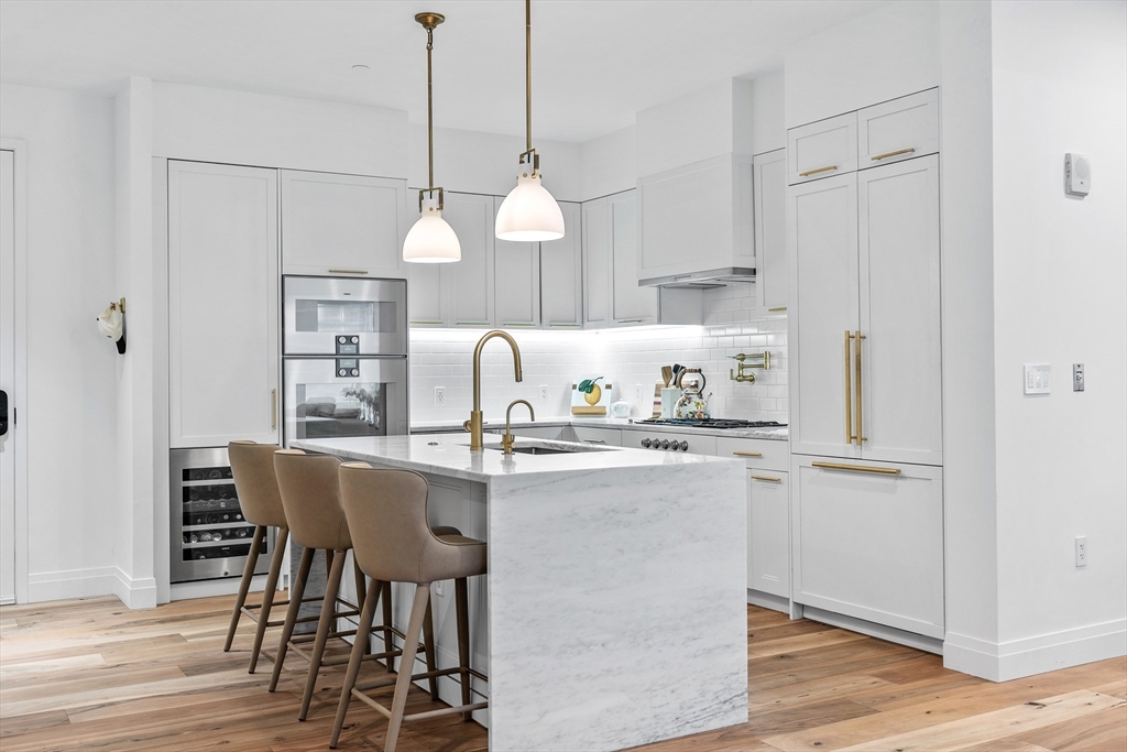 300 Pier 4 Blvd., Unit PHR Boston, MA 02210 - Photo 2 of 28 a kitchen with stainless steel appliances a dining table chairs and white cabinets