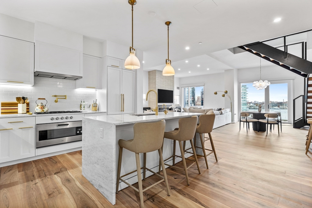 300 Pier 4 Blvd., Unit PHR Boston, MA 02210 - Photo 5 of 28 a kitchen with stainless steel appliances a dining table chairs stove and white cabinets
