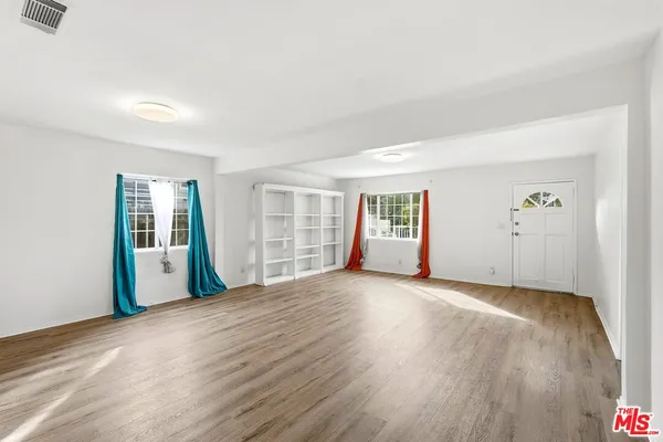 an empty room with wooden floor and windows