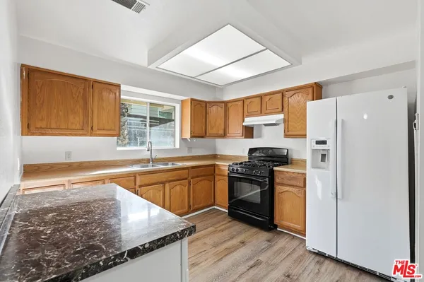 a kitchen with stainless steel appliances granite countertop wooden cabinets a stove a sink and a refrigerator