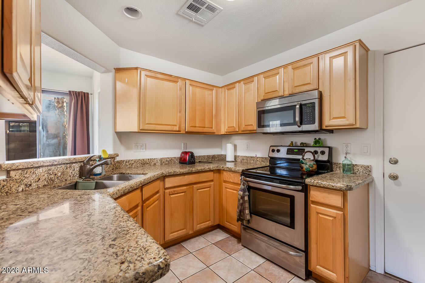 1425 South Lindsay Road, Unit 59 Mesa, AZ 85204 - Photo 7 of 23 a kitchen with stainless steel appliances granite countertop a sink stove and microwave