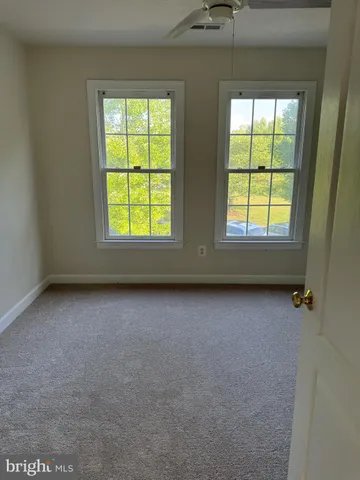 en empty room with windows and ceiling fan