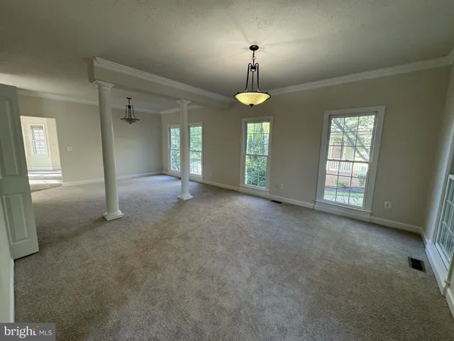 a view of empty room with window and chandelier