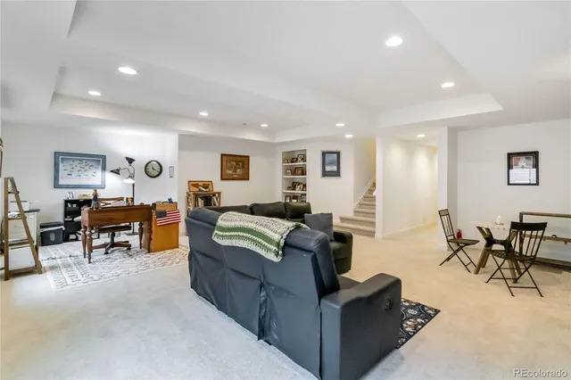 a living room with furniture and a dining table with projector the kitchen
