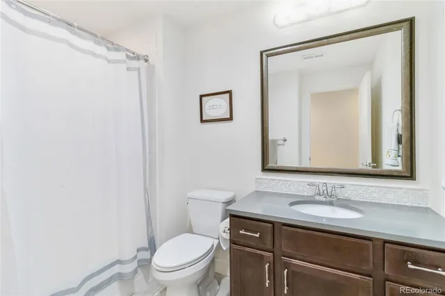 a bathroom with a granite countertop sink toilet and a mirror