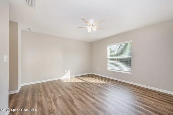 an empty room with wooden floor and windows