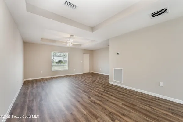 an empty room with wooden floor cabinet and windows