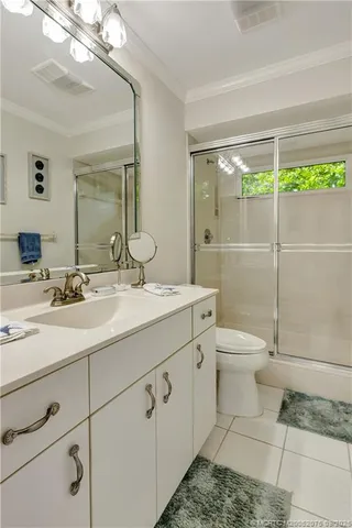 a bathroom with a granite countertop sink a toilet a mirror and shower
