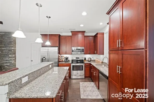 a kitchen with stainless steel appliances granite countertop sink stove and refrigerator