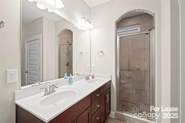 a bathroom with a double vanity sink mirror and shower