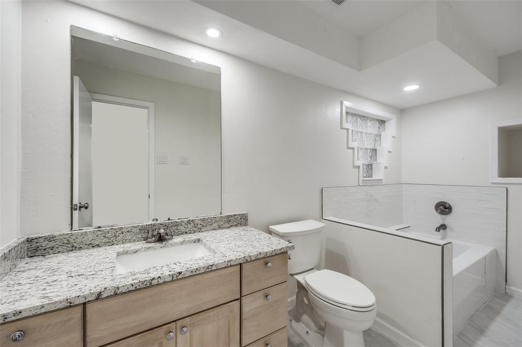 9838 Baseline Drive Dallas, TX 75243 - Photo 23 of 33 a bathroom with a granite countertop sink a toilet and a mirror