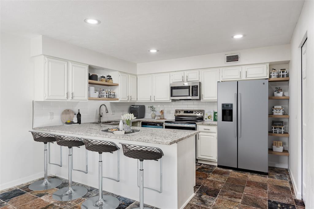 9838 Baseline Drive Dallas, TX 75243 - Photo 9 of 33 a kitchen with white cabinets and stainless steel appliances