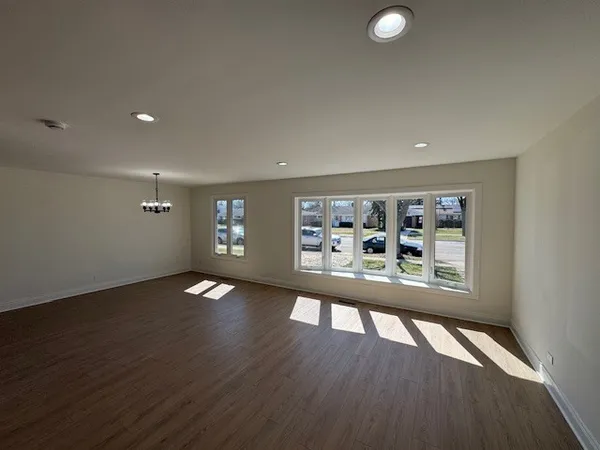 a view of a big room with wooden floor and windows