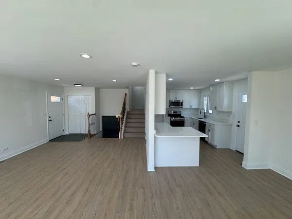 a view of a kitchen with kitchen island wooden floors appliances and cabinets