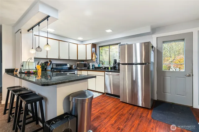 a kitchen with kitchen island granite countertop wooden floors and white appliances