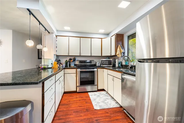 a kitchen with stainless steel appliances granite countertop a stove a sink and a refrigerator
