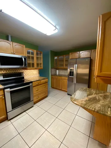 a kitchen with granite countertop a refrigerator and a stove top oven