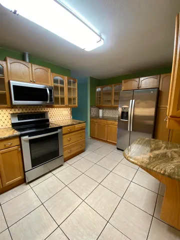 a kitchen with granite countertop a stove a microwave and a sink