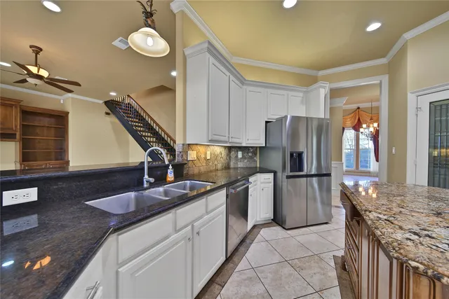 a view of an empty room with chandelier fan and windows