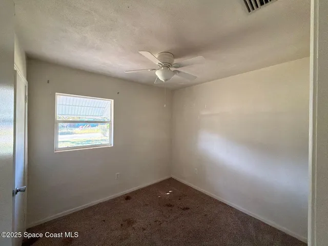 an empty room with a window and a fan