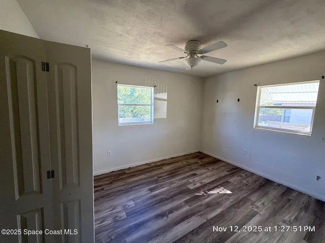 a view of an empty room with wooden floor and a window